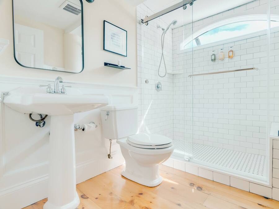 Un baño moderno con lavamanos, inodoro y ducha blancos.