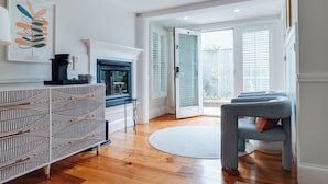 A modern living room with a fireplace, a patterned console table, a round rug, and a seating area with a blue chair.