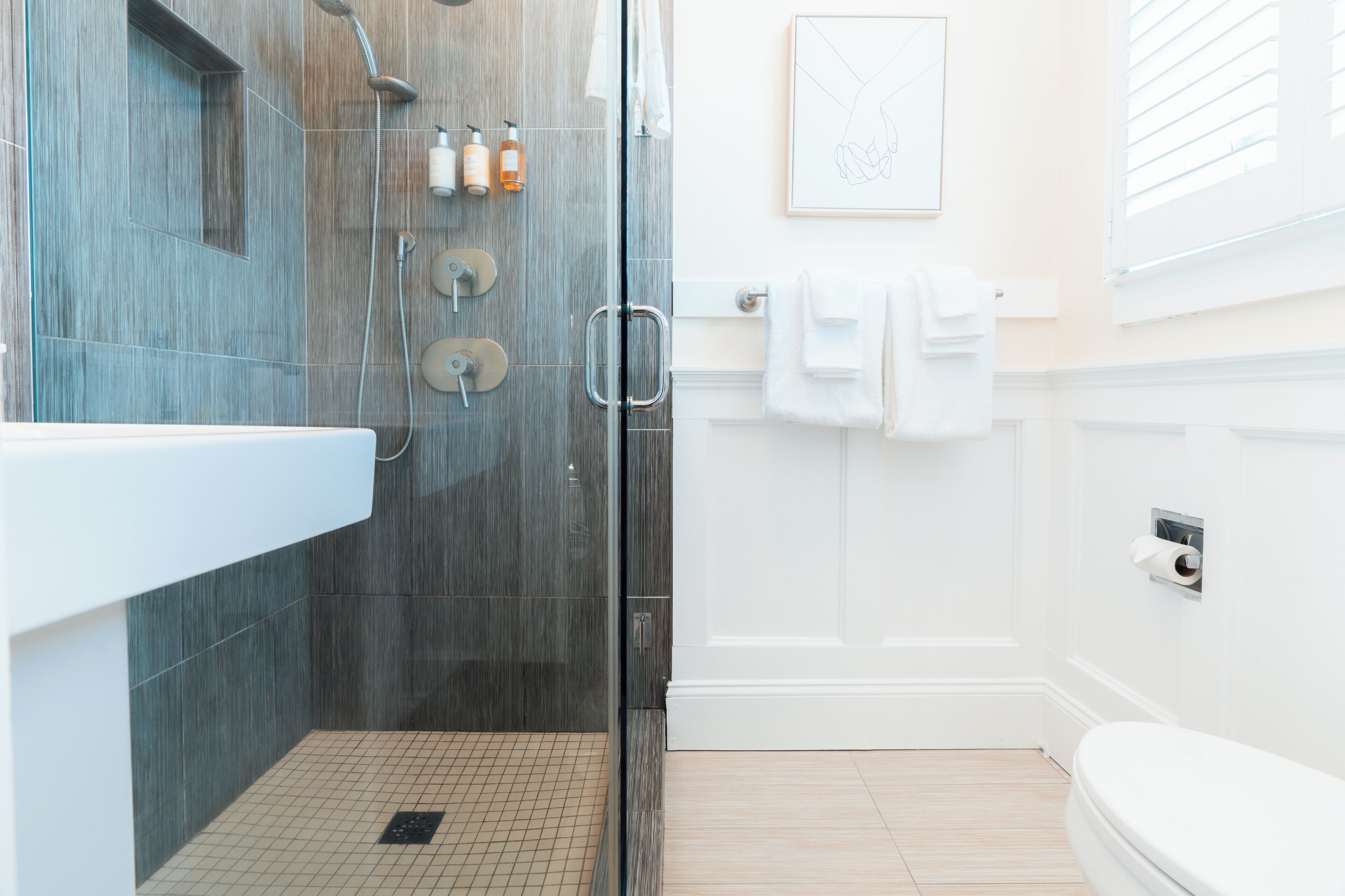 A modern bathroom with a glass-enclosed shower, a white sink, and a toilet.