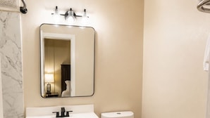Un baño con tocador blanco, inodoro y espejo con iluminación.