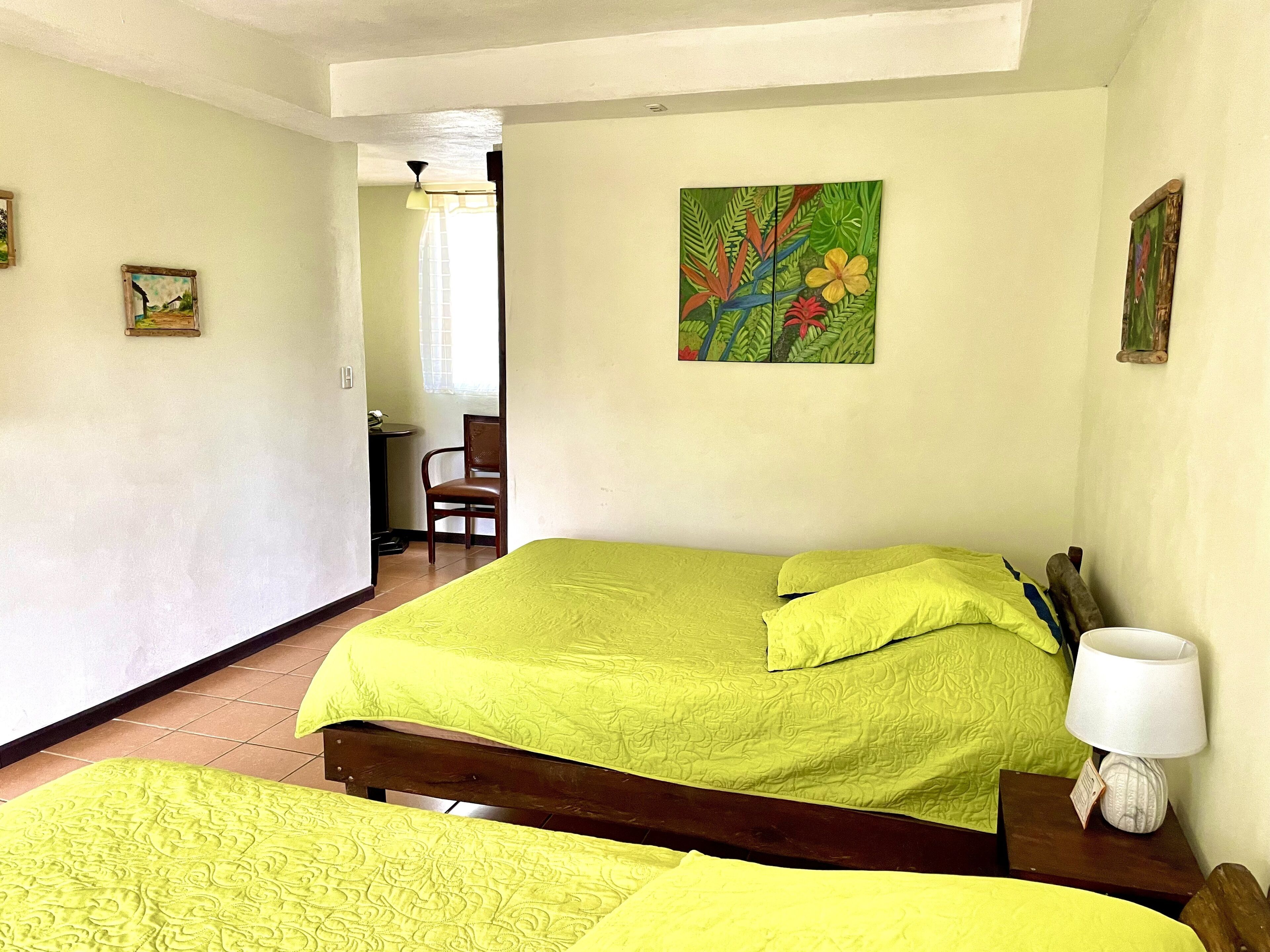 Una habitación con una cama, una silla, un escritorio y un cuadro en la pared.