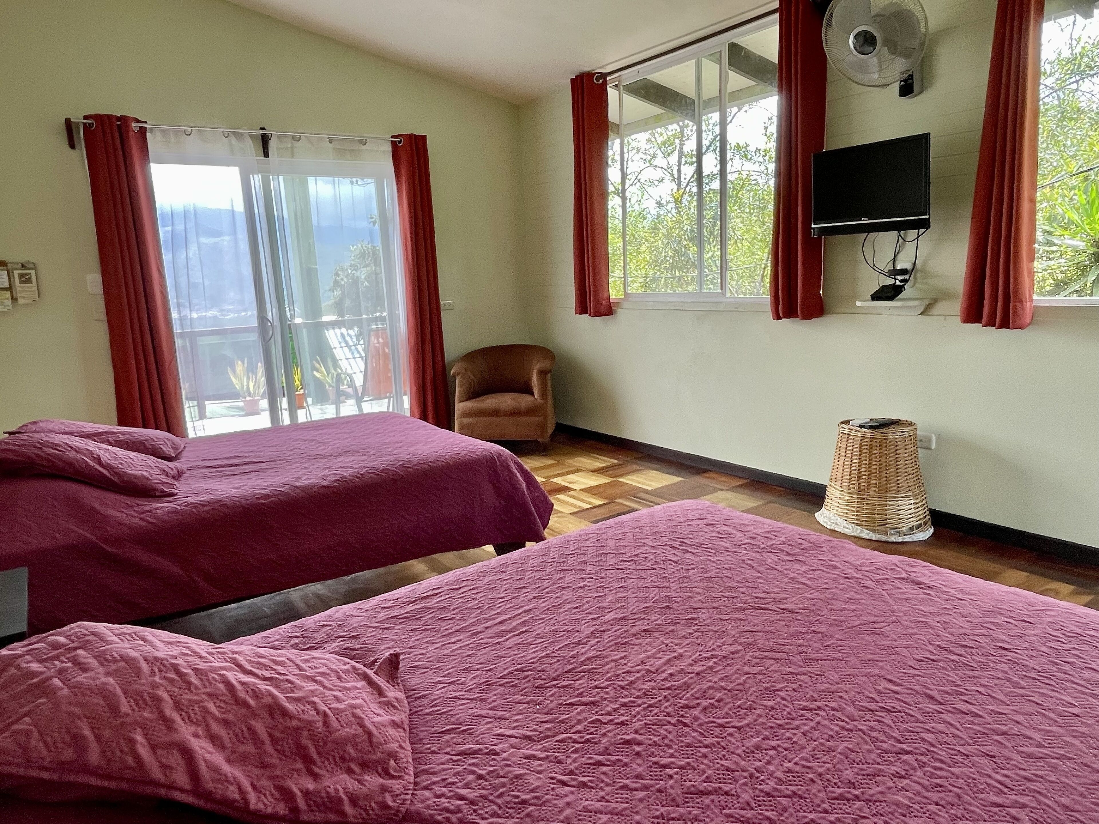 Une chambre avec deux lits, une chaise, un téléviseur et une fenêtre avec des rideaux.