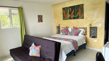 Un dormitorio con una cama, un sofá, una mesita y un estante en la pared.