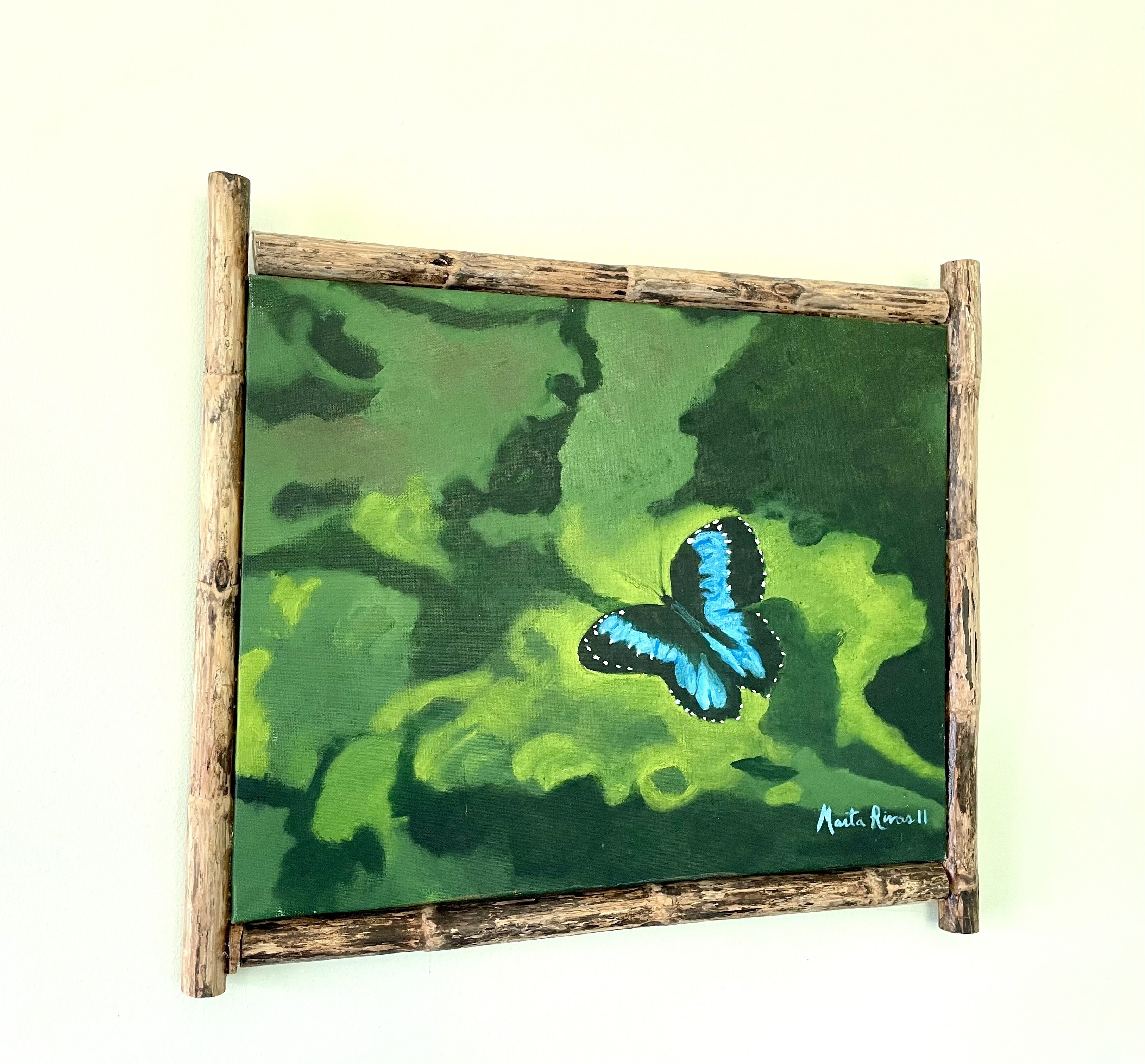 Een lijst met een schilderij van een blauwe vlinder op een groene achtergrond.