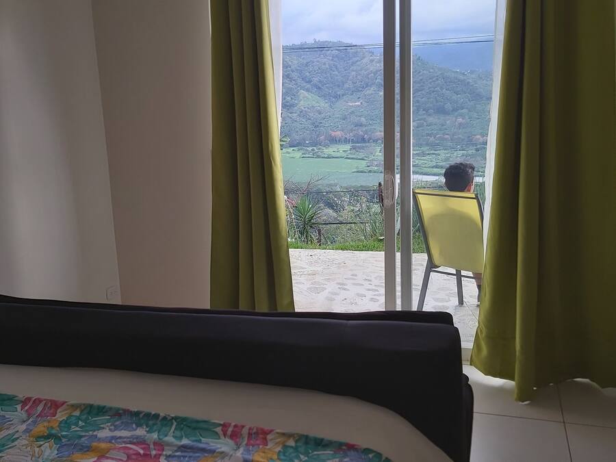 Une chambre à coucher avec un lit, une chaise et une vue sur une colline, visible par la fenêtre.