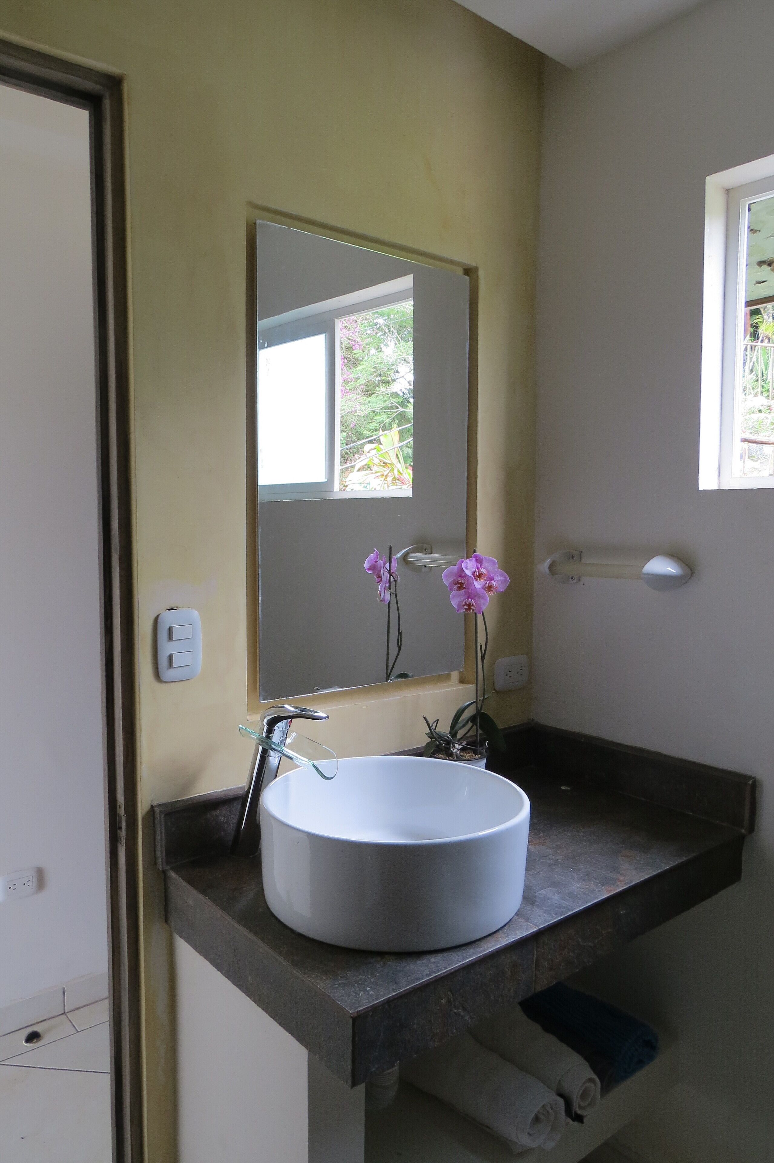 Een badkamer met een wit wastafelmeubel, een spiegel en een raam.