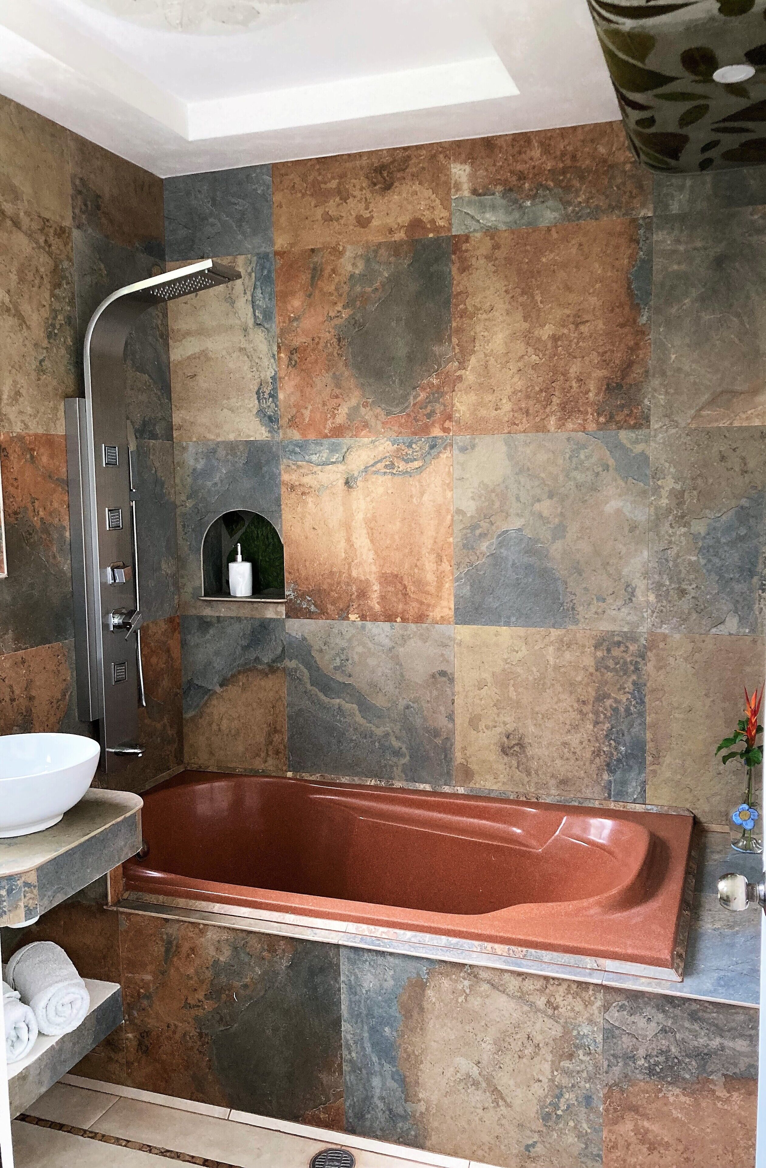 A modern bathroom with a freestanding bathtub, a shower, and a built-in shelf with toiletries.