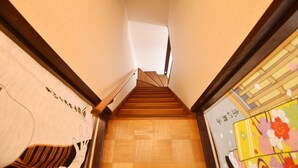 A wooden staircase with a handrail, leading to a landing with a wooden floor.