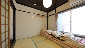 A traditional Japanese room with tatami flooring, a futon bed, a shoji screen, and a sliding door.