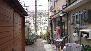 A narrow alleyway with a bicycle and a basket, potted plants, and utility boxes. - Oyado Kyoto Station 2 (Kyoto)