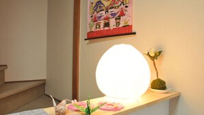 A room with a wooden shelf holding a lit paper lantern, a small potted plant, and a decorative item. - Oyado Kyoto Station 2 (Kyoto)