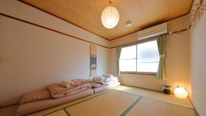 A traditional Japanese room with tatami flooring, a futon bed, a shoji screen, and a hanging paper lantern. - Oyado Kyoto Station 2 (Kyoto)