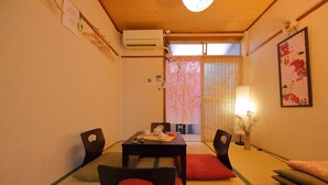 A traditional Japanese room with tatami flooring, a low table with tea set, and a sliding door with floral curtains. - Oyado Kyoto Station 2 (Kyoto)
