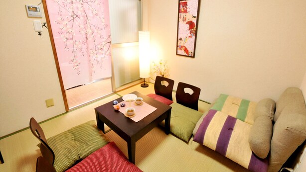 A traditional Japanese room with tatami flooring, a low table with a tea set, and a sofa with cushions. - Oyado Kyoto Station 2 (Kyoto)