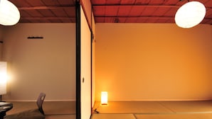 A traditional Japanese room with tatami flooring, a low table with a chair, and two hanging paper lanterns. - Oyado Tofukuji (Kyoto)