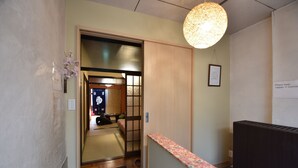 A traditional Japanese room with tatami flooring, a shoji screen door, and a hanging light fixture. - Oyado Tofukuji (Kyoto)