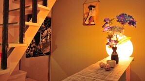 A staircase with a wall-mounted poster, a vase with flowers, and a small table with decorative items. - Oyado Shogoin (Kyoto)