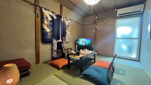 A traditional Japanese room with tatami flooring, a low table with cushions, a television, and a ceiling fan. - Oyado Shogoin (Kyoto)