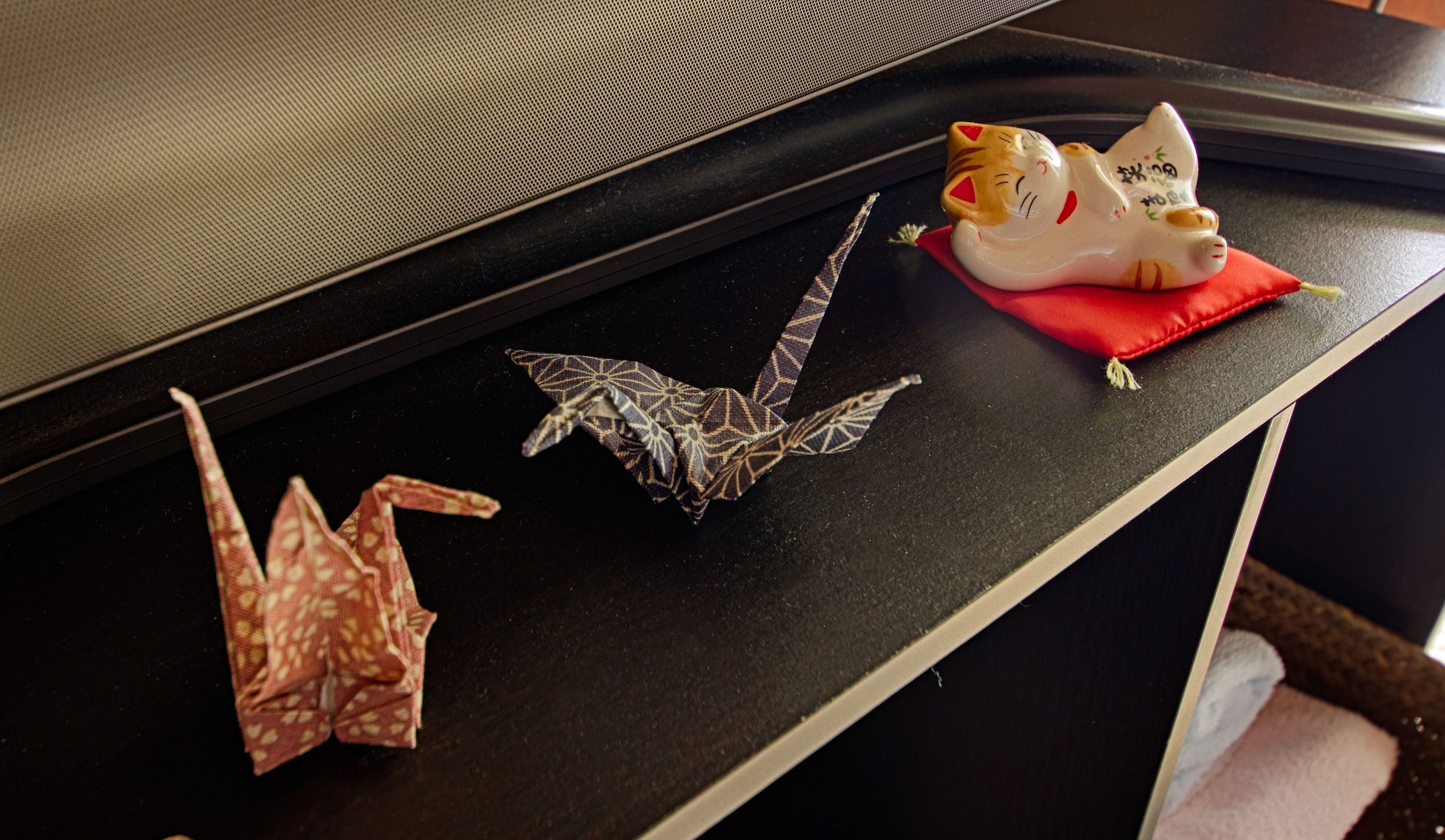 A black table with a white edge, a decorative cat figurine, and origami figures.