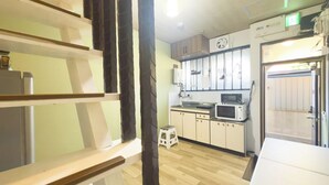 A kitchen with wooden cabinets, a microwave, and a small stool. - Oyado Shogoin (Kyoto)