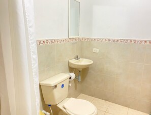 Une petite salle de bain avec des toilettes, un lavabo et un miroir.