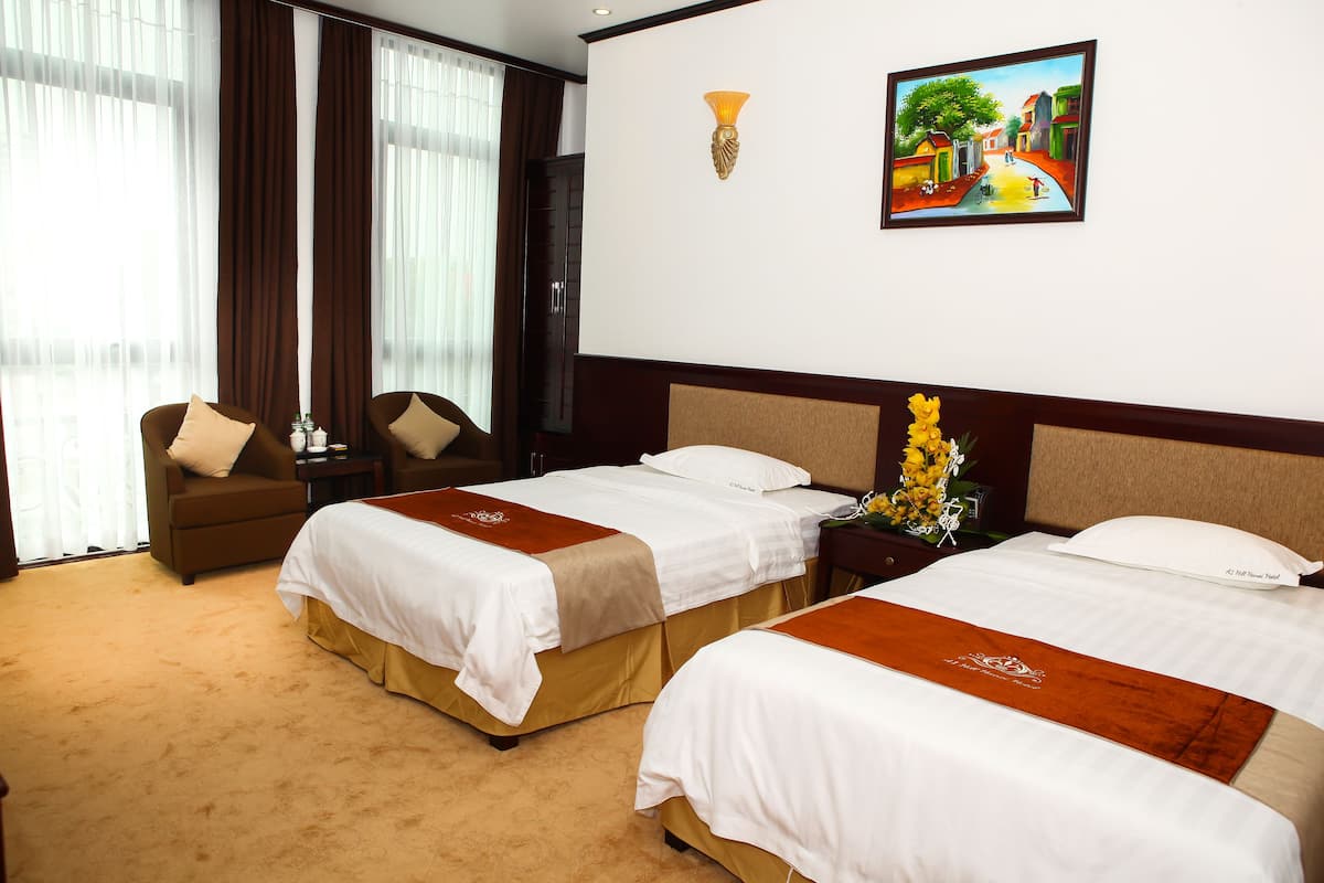 A hotel room with two beds, a nightstand, a chair, and a painting on the wall.