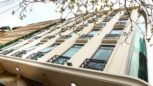 Um edifício de vários andares com fachada bege, janelas grandes e grades de ferro decorativas nas varandas.