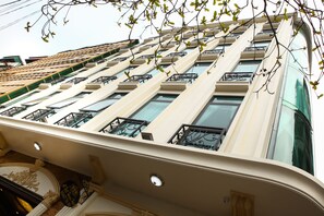 Un edificio de varios pisos con fachada color crema, ventanas amplias y barandillas de hierro decorativas en los balcones.