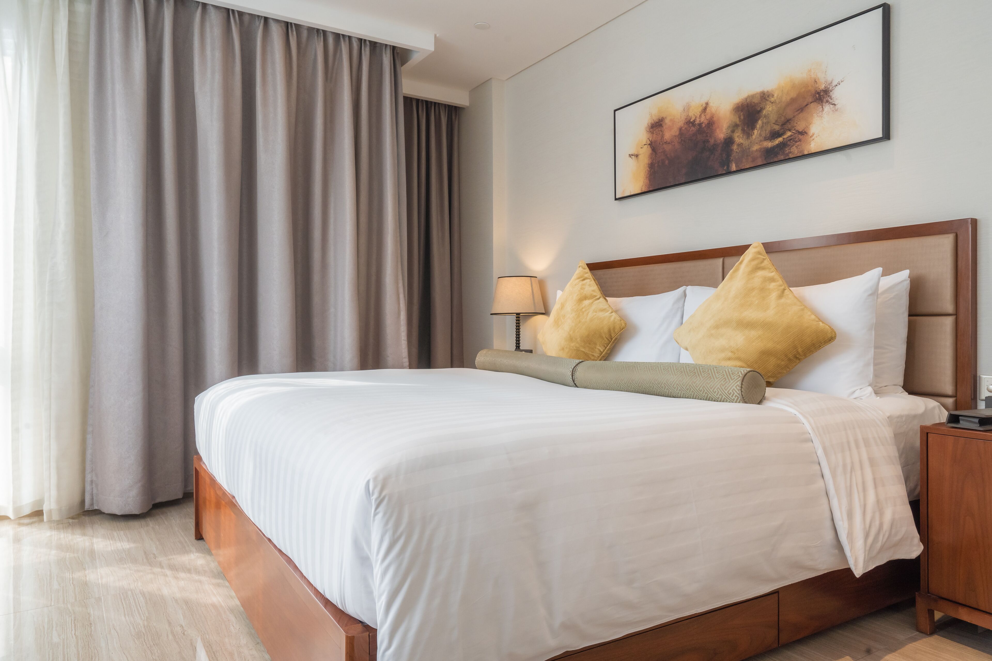 Une chambre d’hôtel avec un grand lit, une tête de lit en bois, une table de chevet et un tableau au mur.