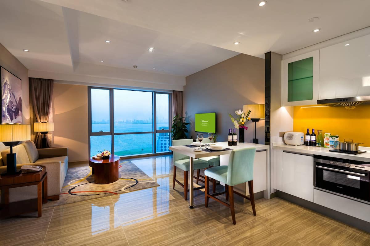 Ein modernes Hotelzimmer mit Essbereich, Küchenzeile und großem Fenster mit Blick auf die Stadt.