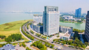 Un hôtel moderne, reconnaissable à son grand panneau « Oakwood », situé dans un quartier urbain bien aménagé, avec des rues et des espaces verts.
