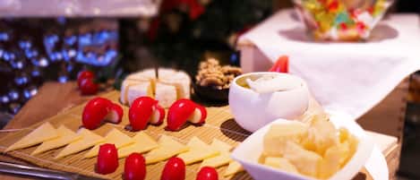 Uma mesa com diversos alimentos, incluindo queijo, tomates e uma tigela de purê de batatas.