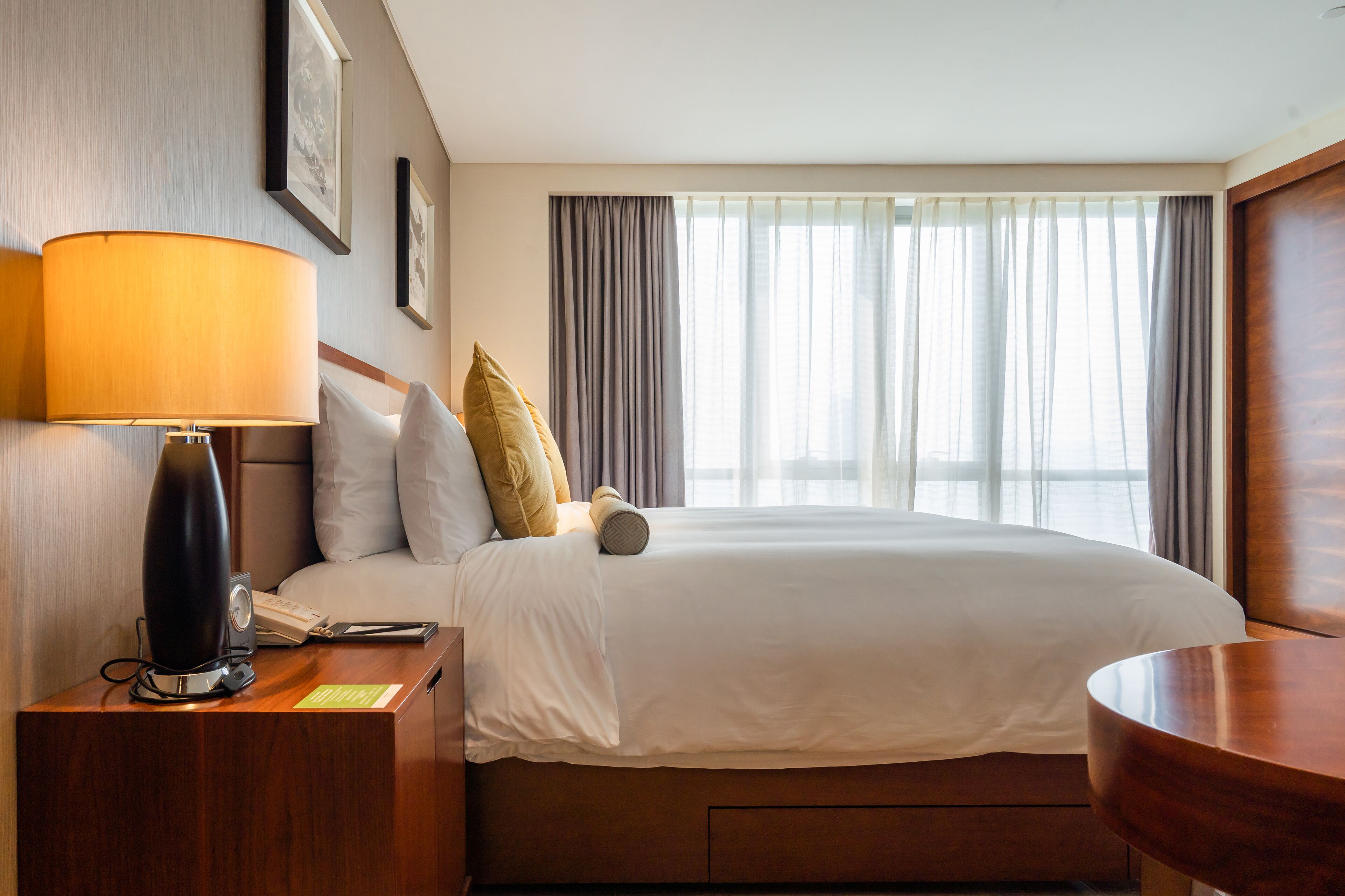 Une chambre d’hôtel avec un lit, une table de chevet avec une lampe, un téléphone et une petite table.