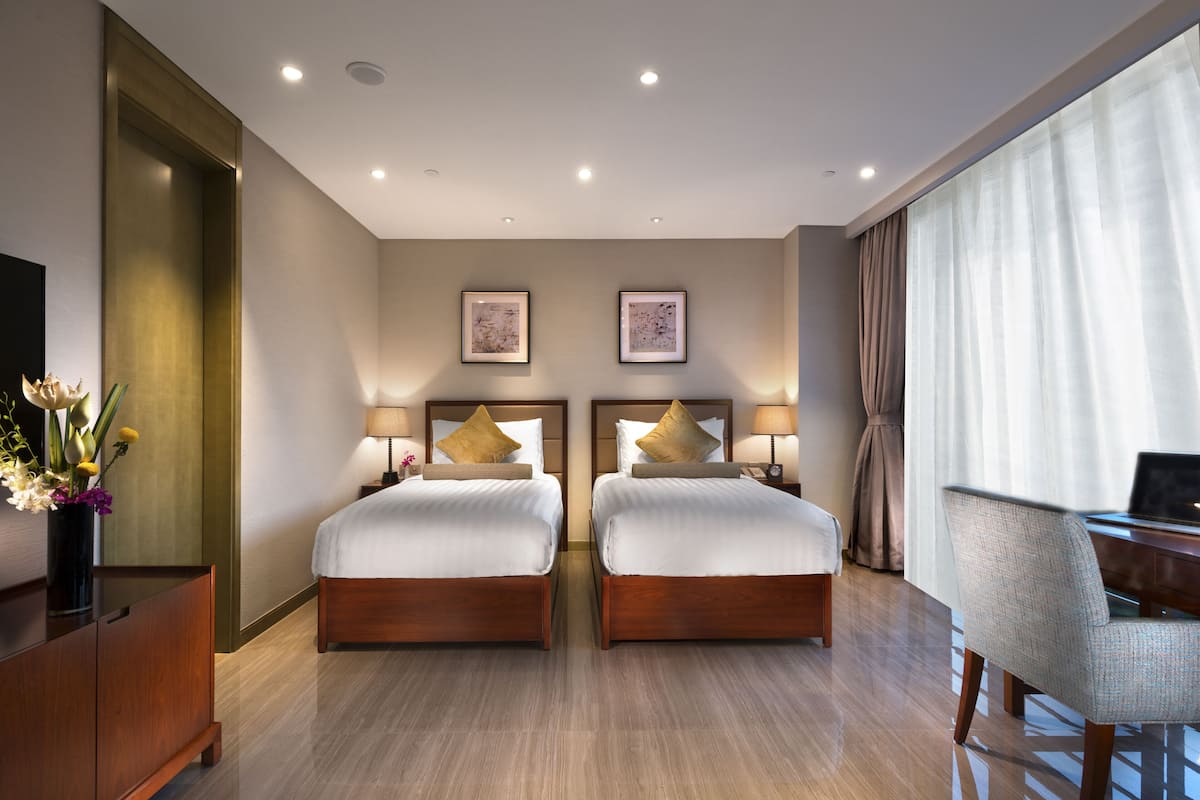 Ein Hotelzimmer mit zwei Betten, einem Schreibtisch und einem Stuhl.