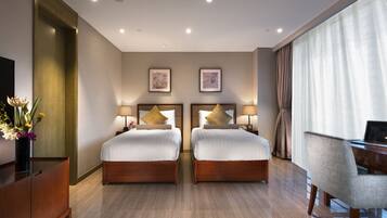 A hotel room with two beds, a desk, and a chair.