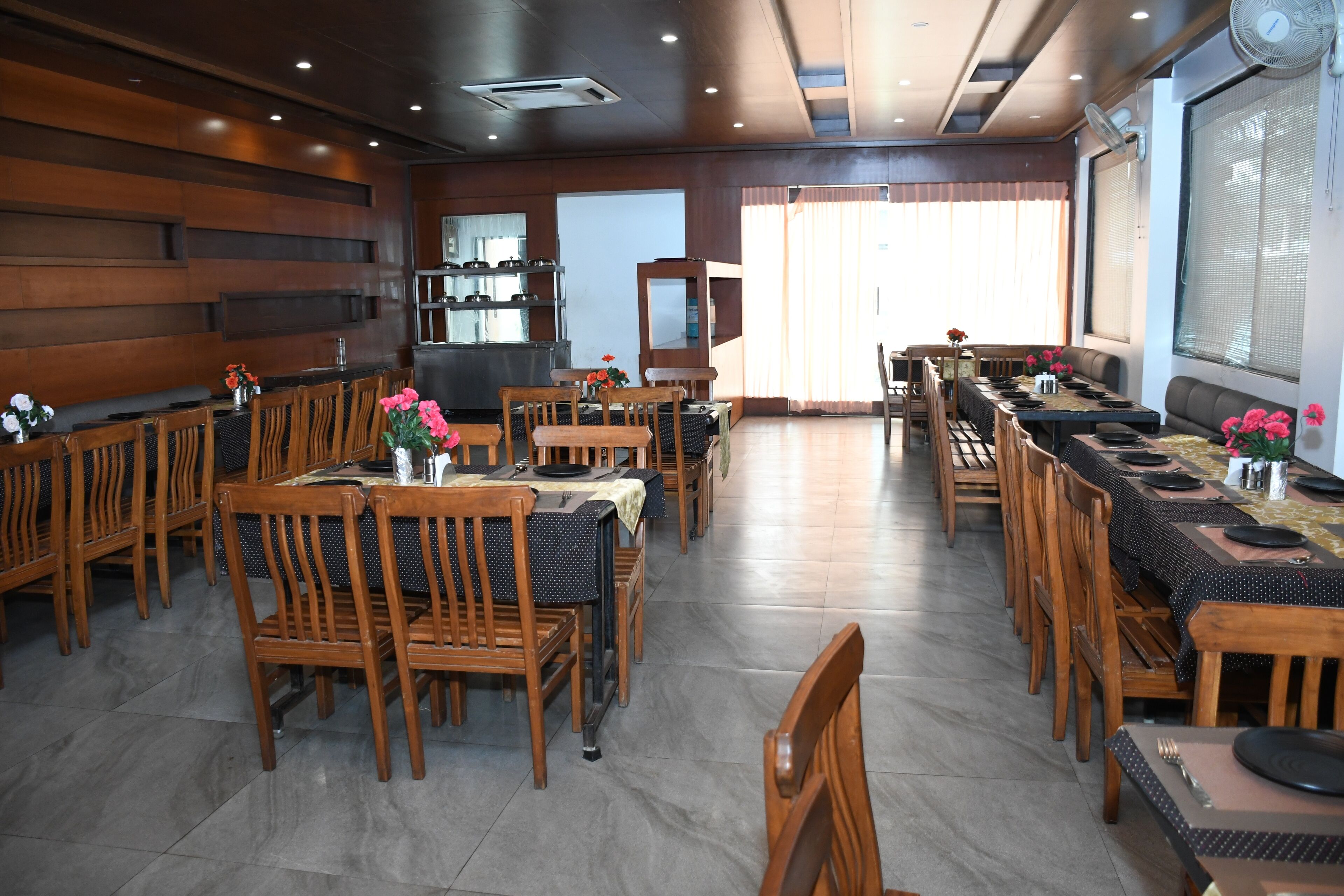 Un restaurante con mobiliario de madera, una mesa larga y una zona de cocina.
