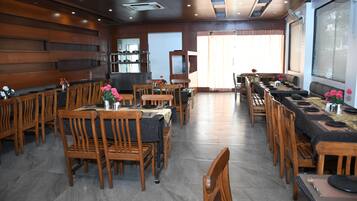 Un restaurante con mobiliario de madera, una mesa larga y una zona de cocina.