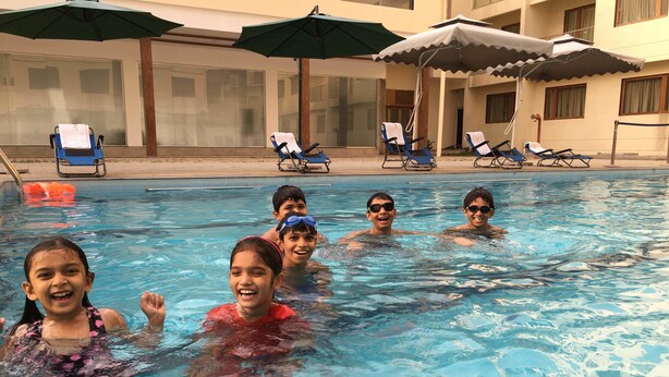 A swimming pool with lounge chairs and umbrellas. - Hotel Pushpak Resort (Rahata)