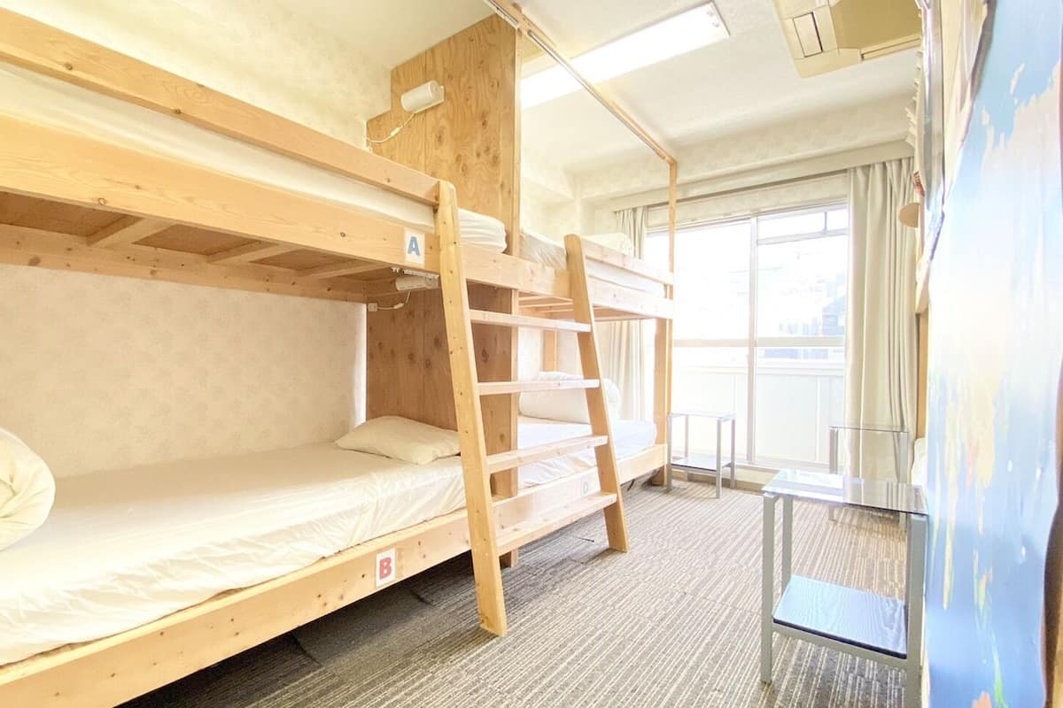 A bunk bed room with a ladder, a window, and a view of the outside.