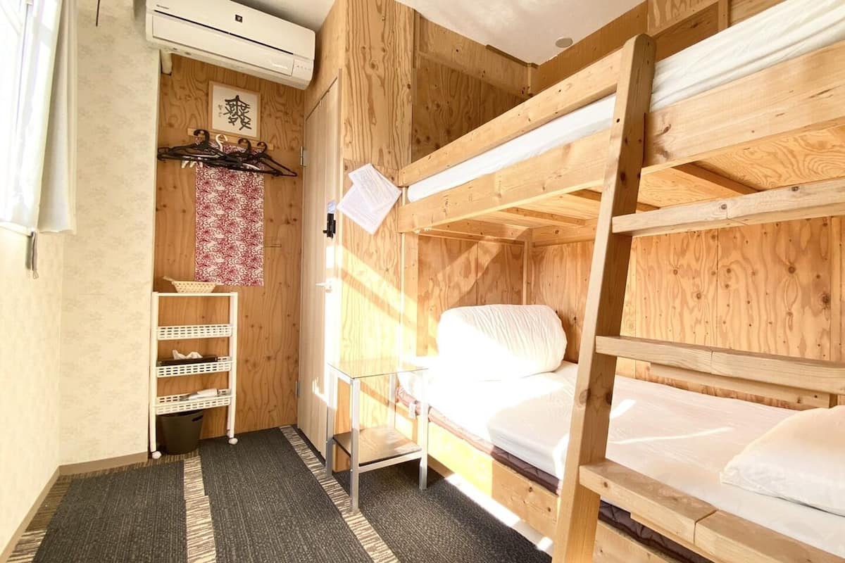 A wooden bunk bed room with a small desk and shelves.