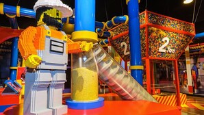 Ein farbenfroher Spielbereich drinnen mit einer großen, gelben Rutsche, einer Spielkonstruktion und einem Schild mit der Aufschrift '2 Ton'.