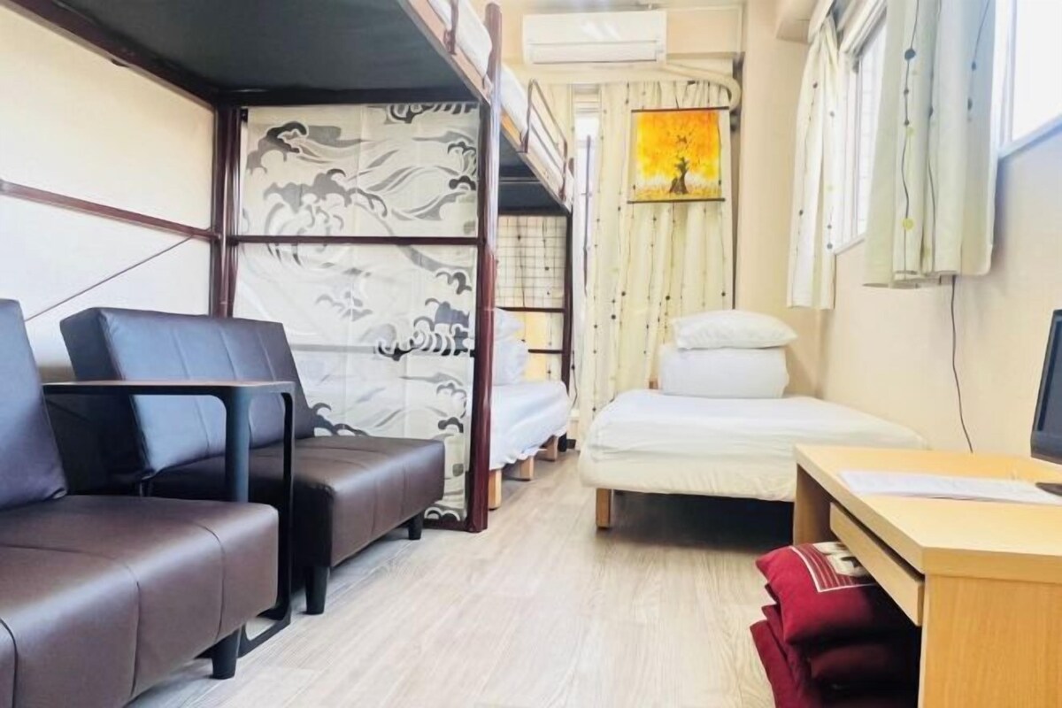 Habitación pequeña con literas, un escritorio y una zona de estar.