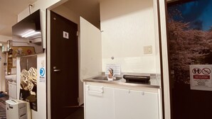 Ein Hotelzimmer mit Bad, Waschbecken und Spiegel. Ein Schild weist auf eine rutschfeste Zone hin.