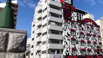 A multi-story building with balconies, a sign for a guest house, and a decorative facade with red accents.