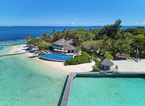 An aerial view of a resort with a swimming pool, beach, and thatched-roof structures. - NH Maldives Kuda Rah Resort (Kuda Rah)