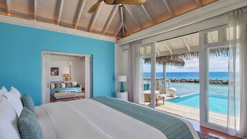 Ein Schlafzimmer mit einem großen Bett, einem Deckenventilator und Blick auf einen Pool und das Meer.