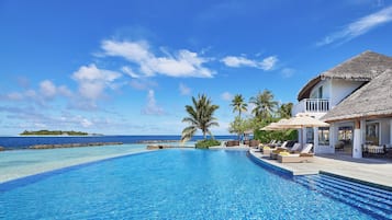 Una piscina al aire libre, sombrillas, sillones reclinables de piscina
