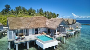 Overwater bungalows with thatched roofs, clear blue water, and lush greenery. - NH Maldives Kuda Rah Resort (Kuda Rah)