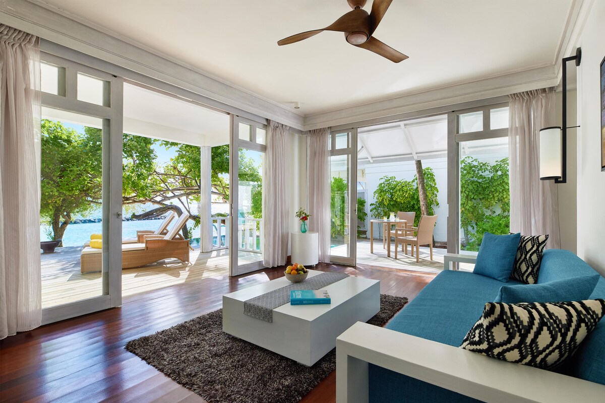 A modern living room with a large sofa, a coffee table, and a ceiling fan.