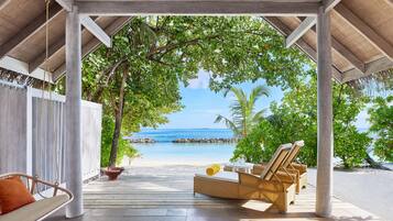 Un espacio de estar al aire libre cubierto con vista a la playa y al océano.